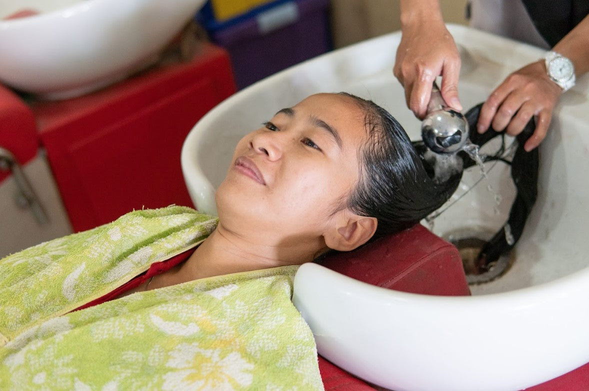 Woman relaxing during a salon hair wash highlighting creambath hair treatment benefits for scalp nourishment and smooth, healthy hair