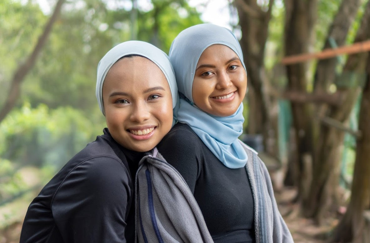 Two women wearing hijab outdoors, representing healthy hair care for hijab wearers and a confident everyday lifestyle